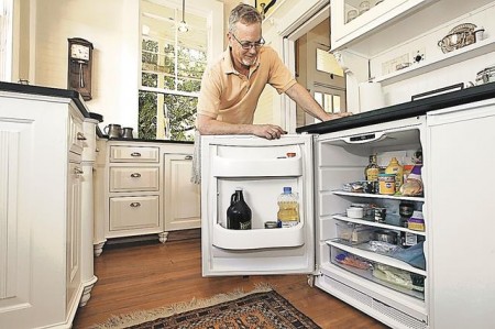 Steen opens the space-saving, under-the-counter refrigerator. The freezer is next to it. The home-office space is at the end of the counter.